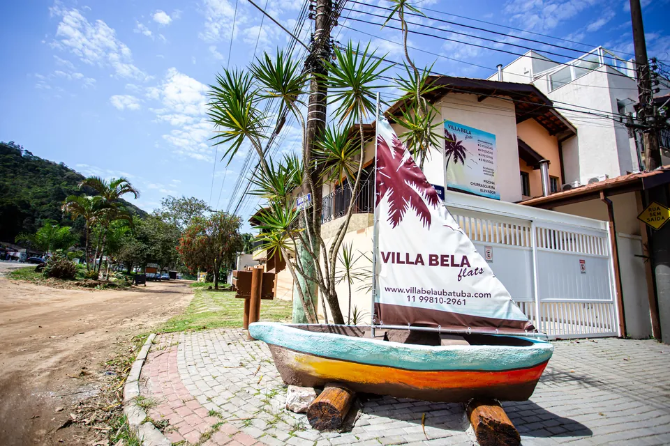 Entrada do Villa Bela Flats, com a placa da casa e o barco decorativo na calçada
