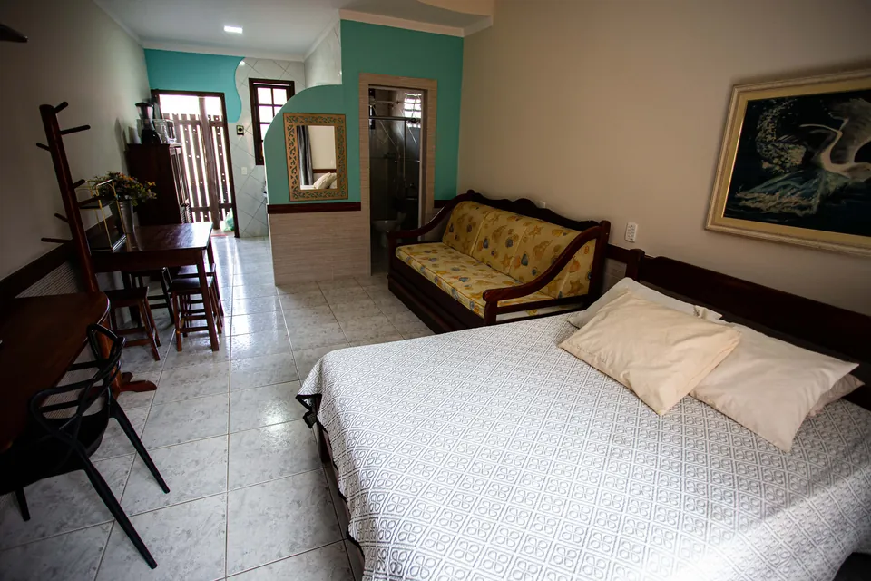 Interior de um flat do Villa Bela, com cama de casal, sala de estar e mesa integradas