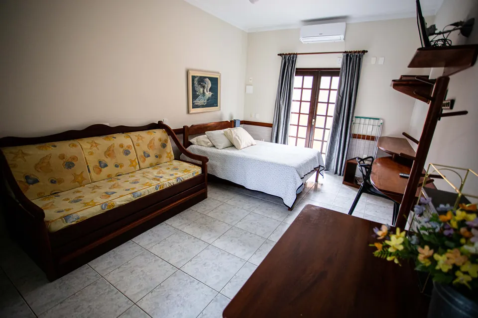 Sala do loft com sofá-cama e a cama de casal ao fundo