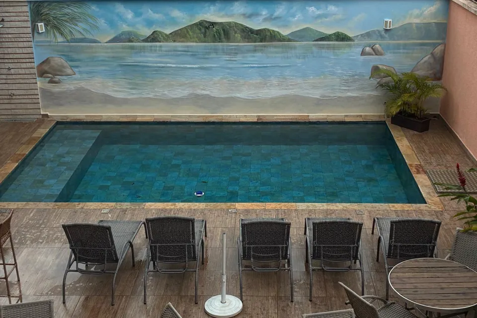 Piscina do Villa Bela vista de cima, com cadeiras e um painel de praia pintado na parede