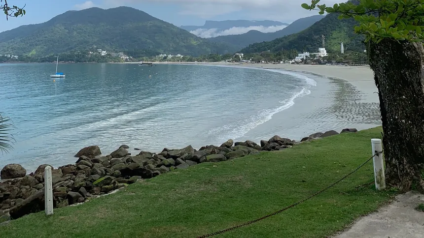 Praia da Enseada em Ubatuba, com mar calmo e a serra ao fundo
