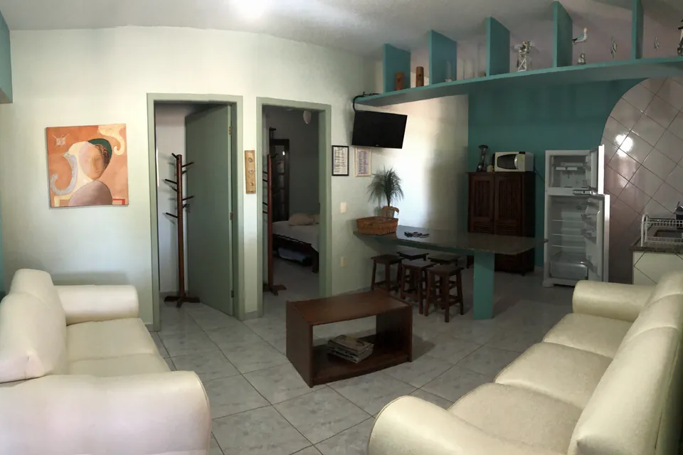 Sala de estar integrada à cozinha no apartamento 102, com sofás e mesa de jantar