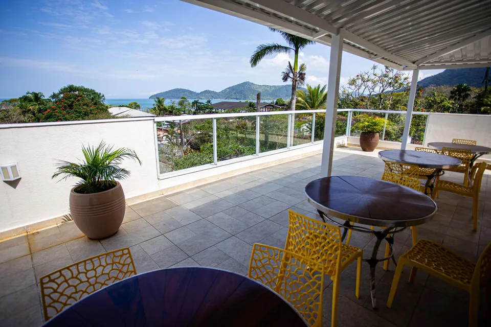 Terraço do Villa Bela com mesas e vista para o mar e a mata